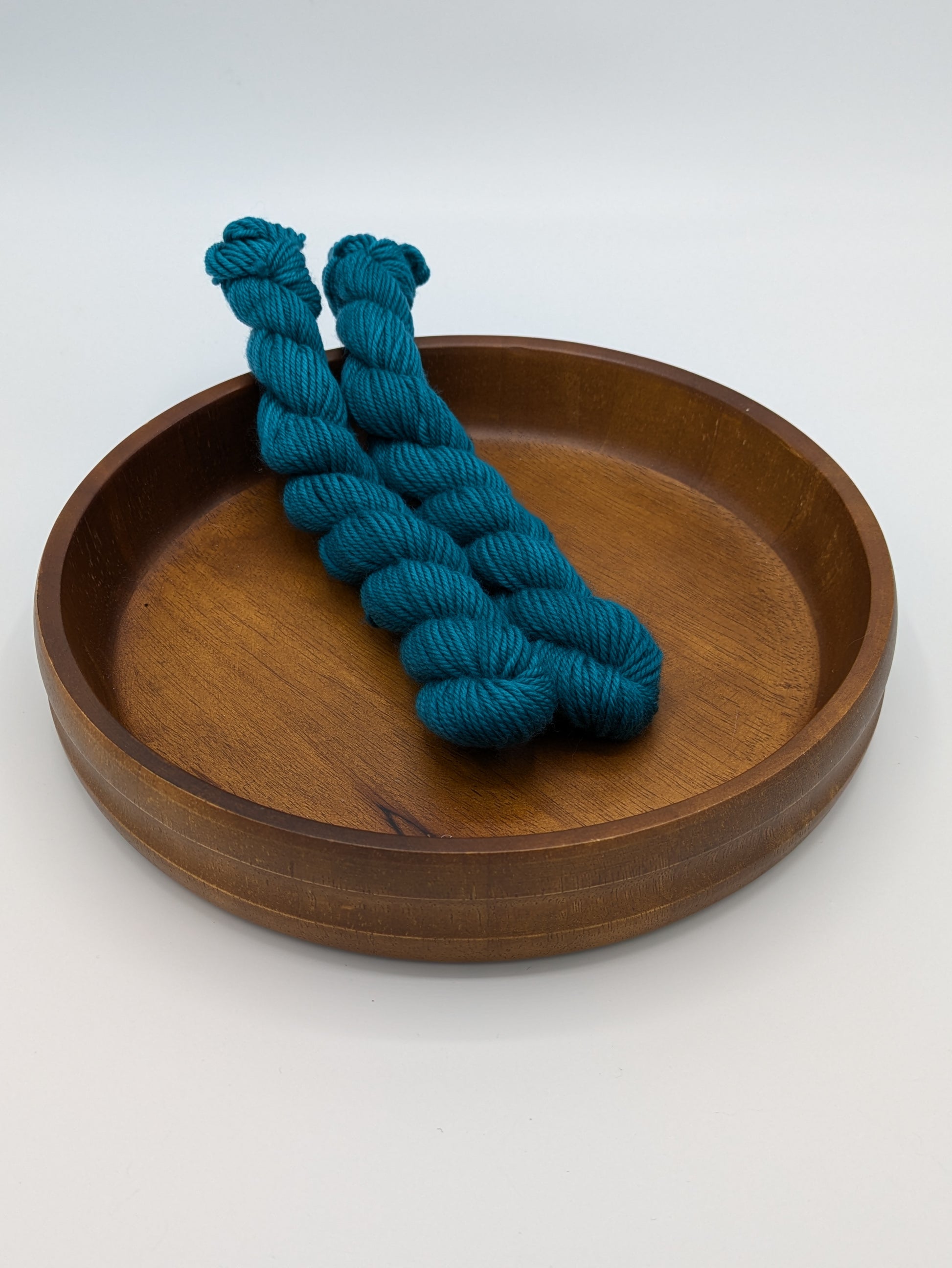 Skeins of Bluegrass DK weight yarn, a medium green blue color