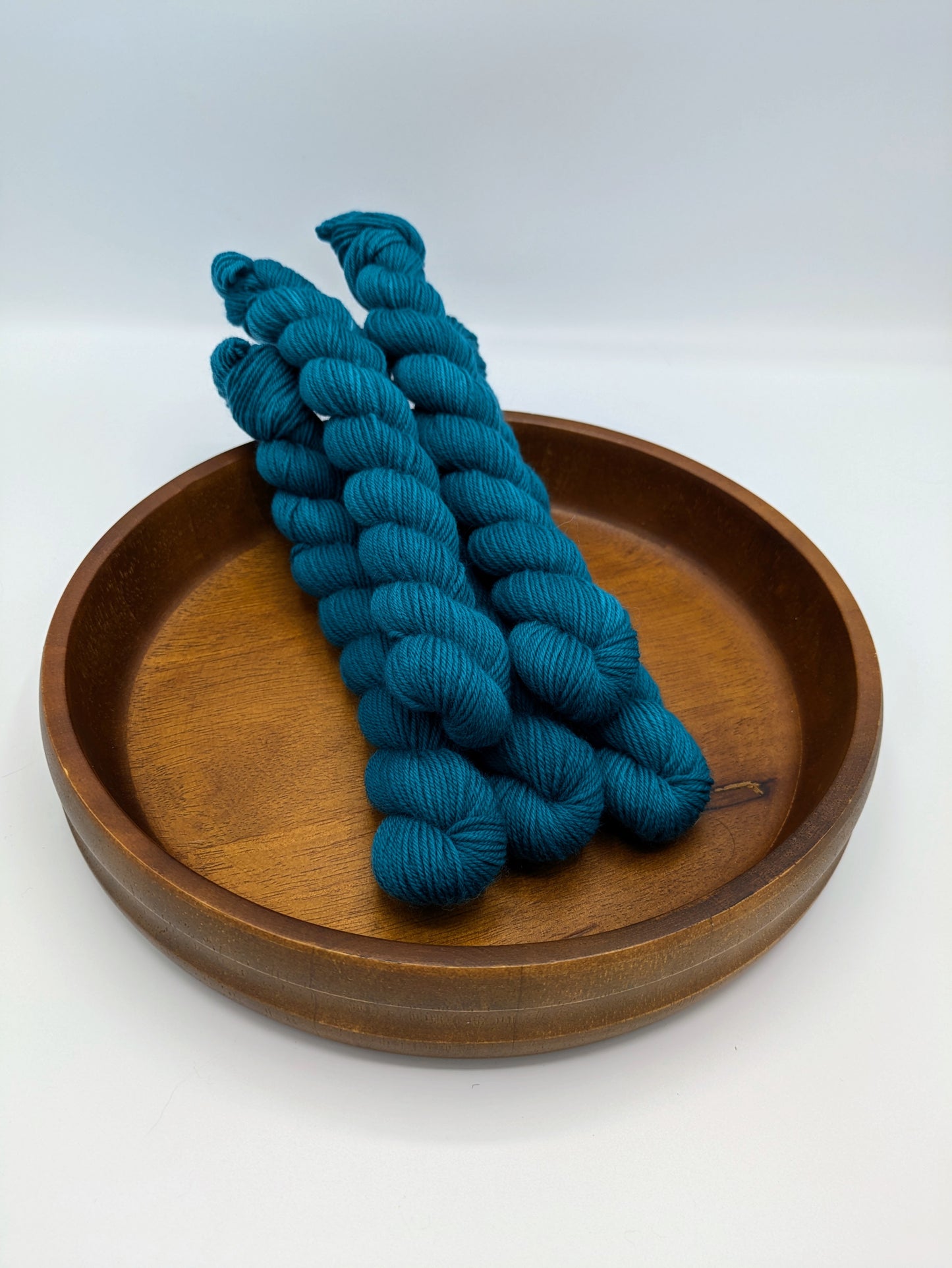 Skeins of Bluegrass fingering weight yarn, a medium green blue color