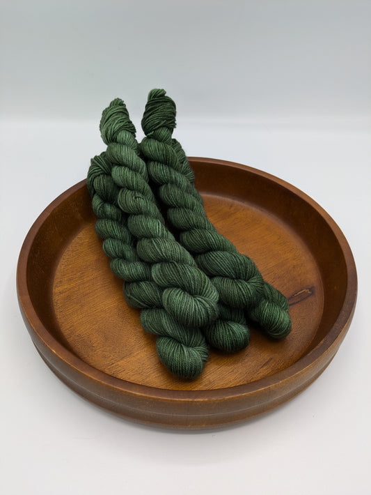 Fir Yarn in 20 gram fingering weight mini skein, showcasing a deep forest green color