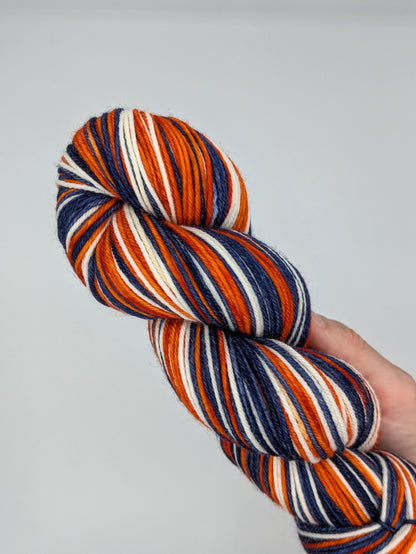 Multicolored striped yarn held in a hand against a plain background