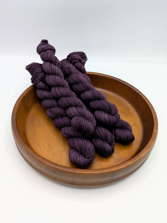 Skeins of Grandma fingering weight yarn, a deep dark purple color