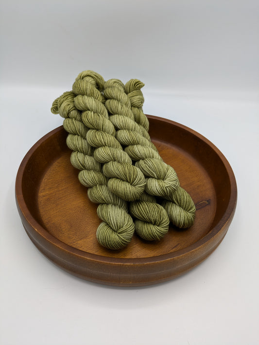 Skeins of Grasshopper fingering weight yarn, a soft green color