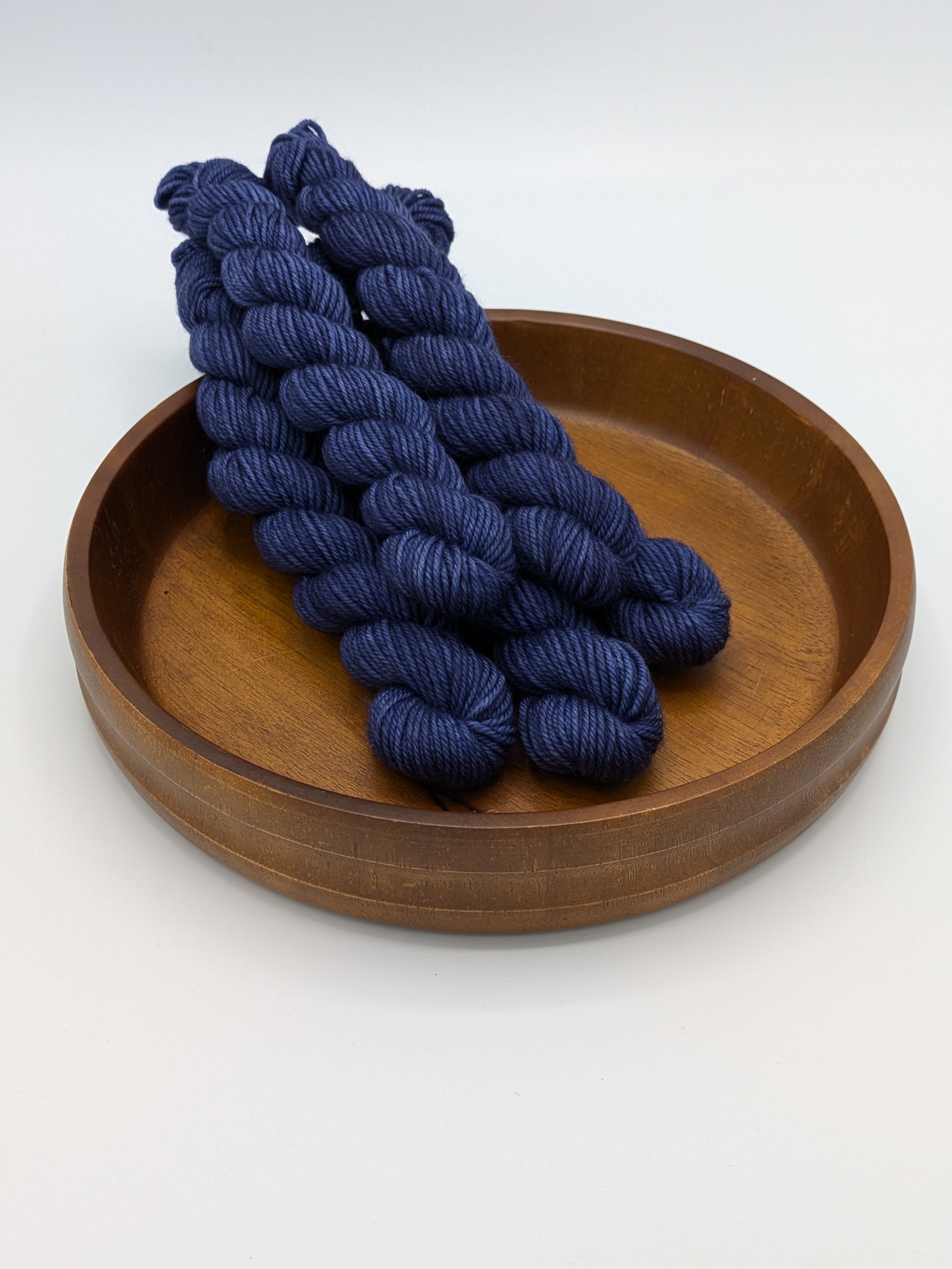 Skeins of Mountain Shadows DK weight yarn, a dark blue color