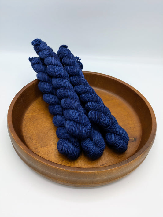 Skeins of Mountain Shadows fingering weight yarn, a dark blue color