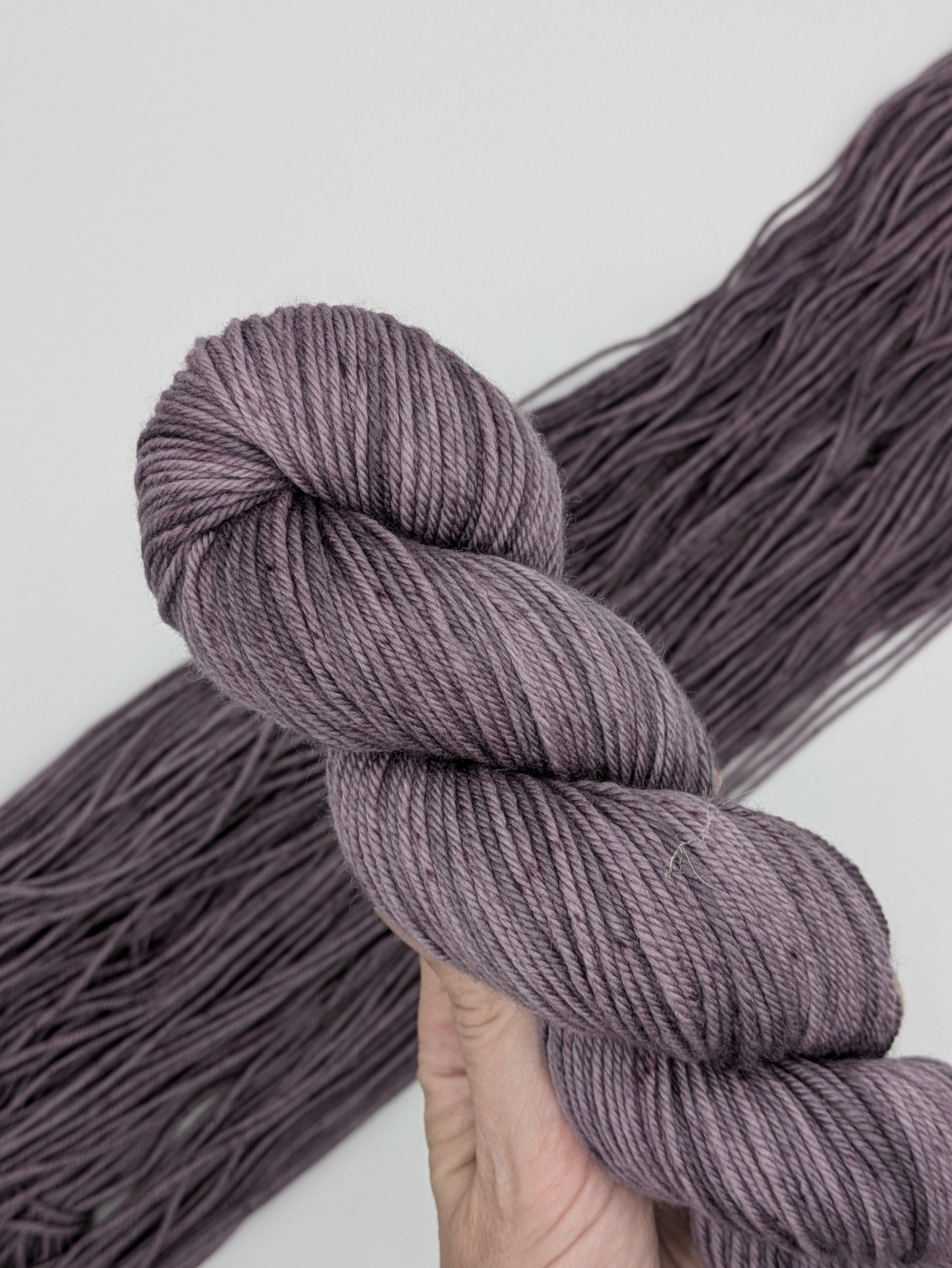 Amethyst Yarn skein in non-superwash DK yarn, showcasing hand-dyed soft purple color 