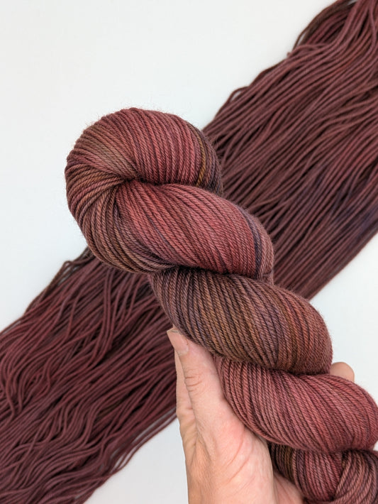 Cocoa Non-Supewash Yarn skein in DK weight, showcasing red brown variegated color