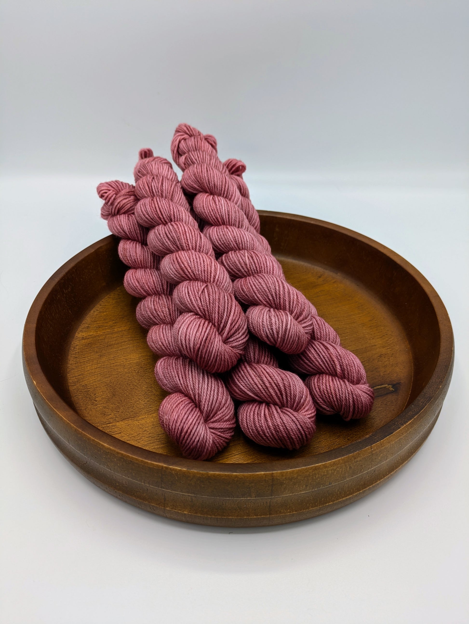 Skeins of Peony Whisper fingering weight yarn, a soft pink color