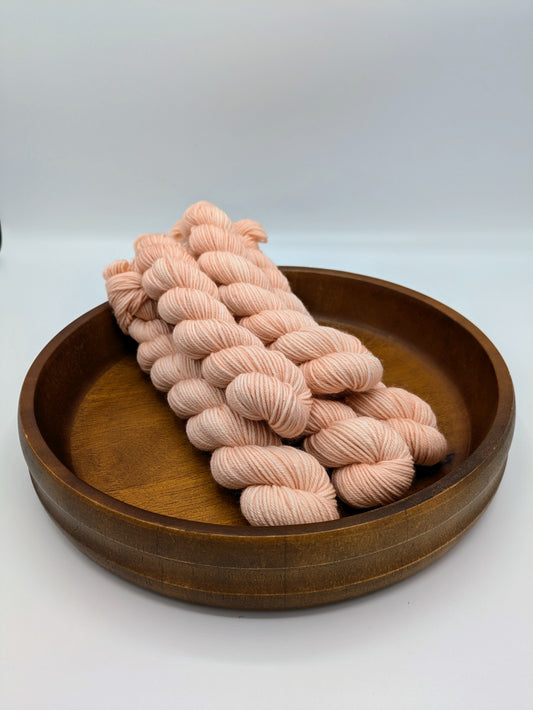 Rose Petal Yarn mini skeins in fingering weight, showing a soft coral color