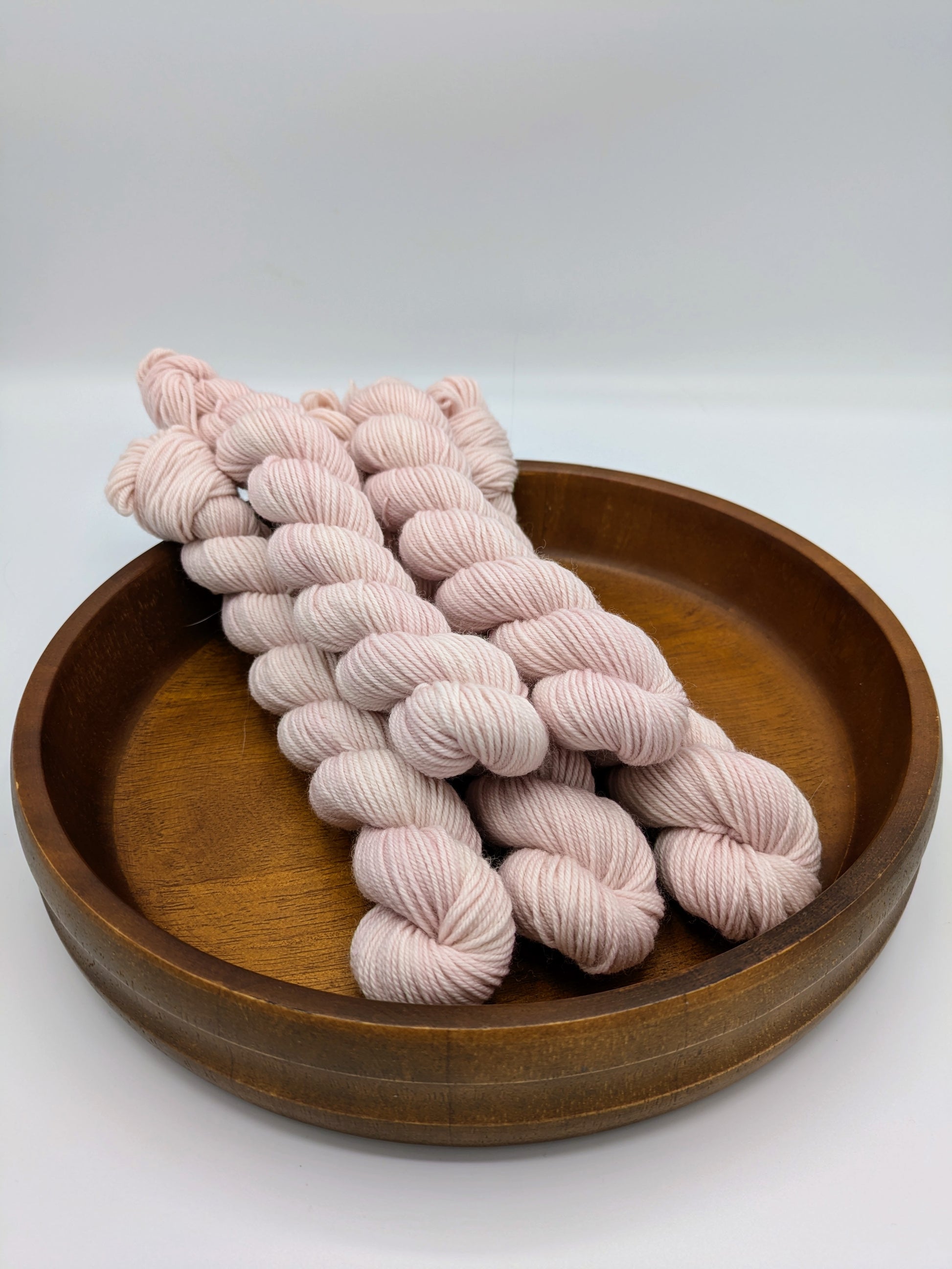 Seashell mini skeins in a fingering weight yarn, showing a soft pink color