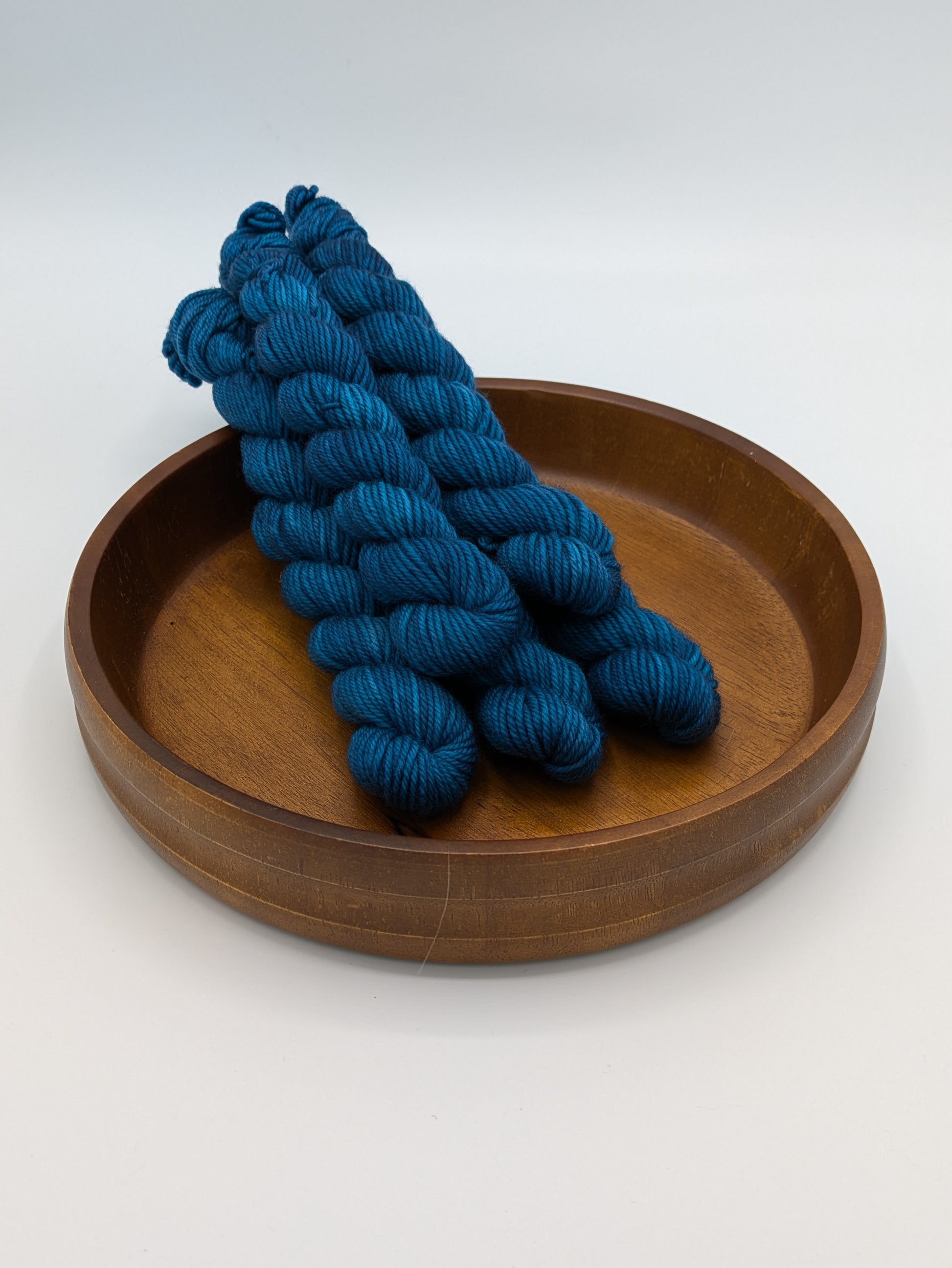 Skeins of Tealicious DK weight yarn, a dark bold blue color