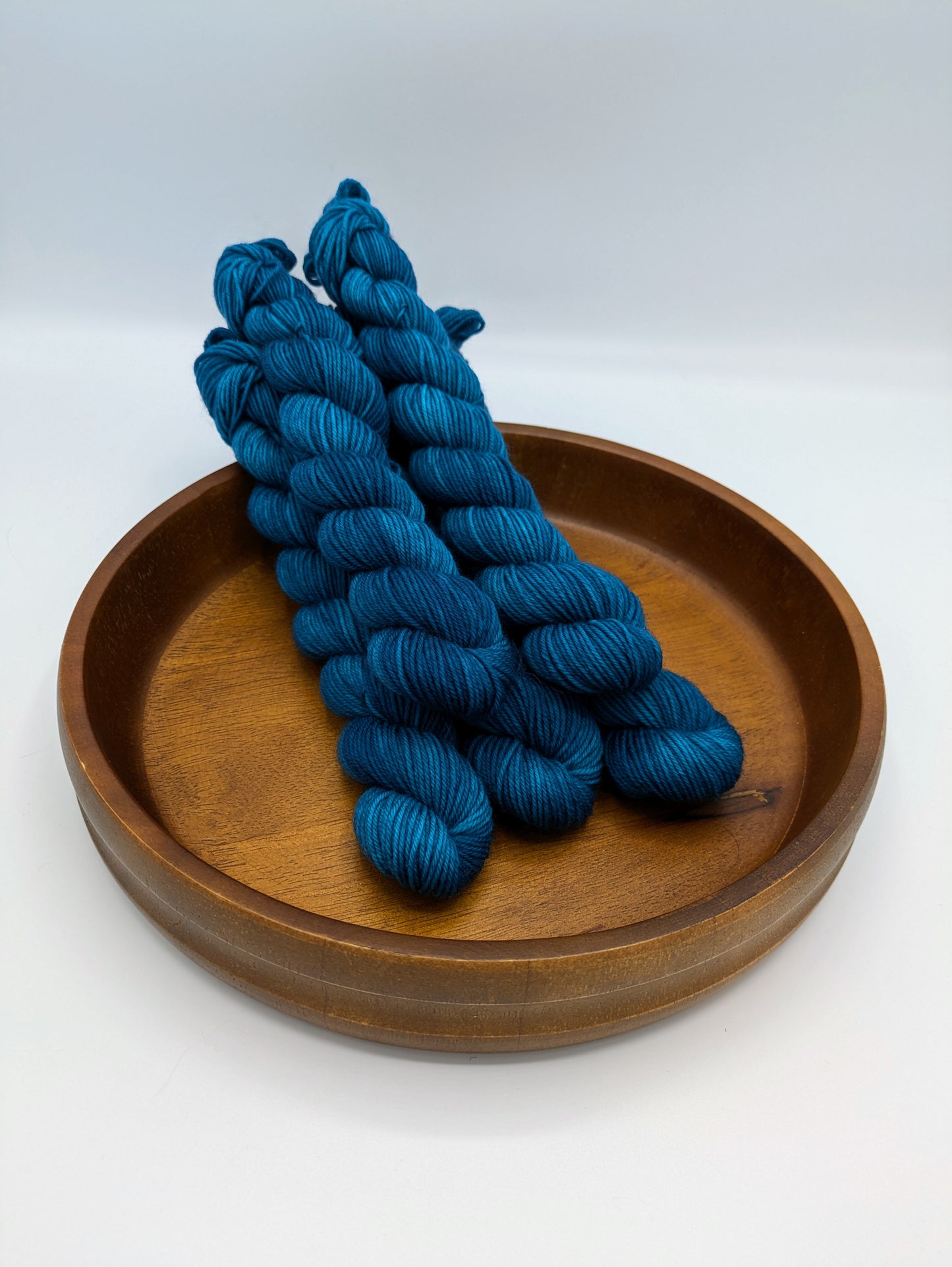 Skeins of Tealicious fingering weight yarn, a dark bold blue color