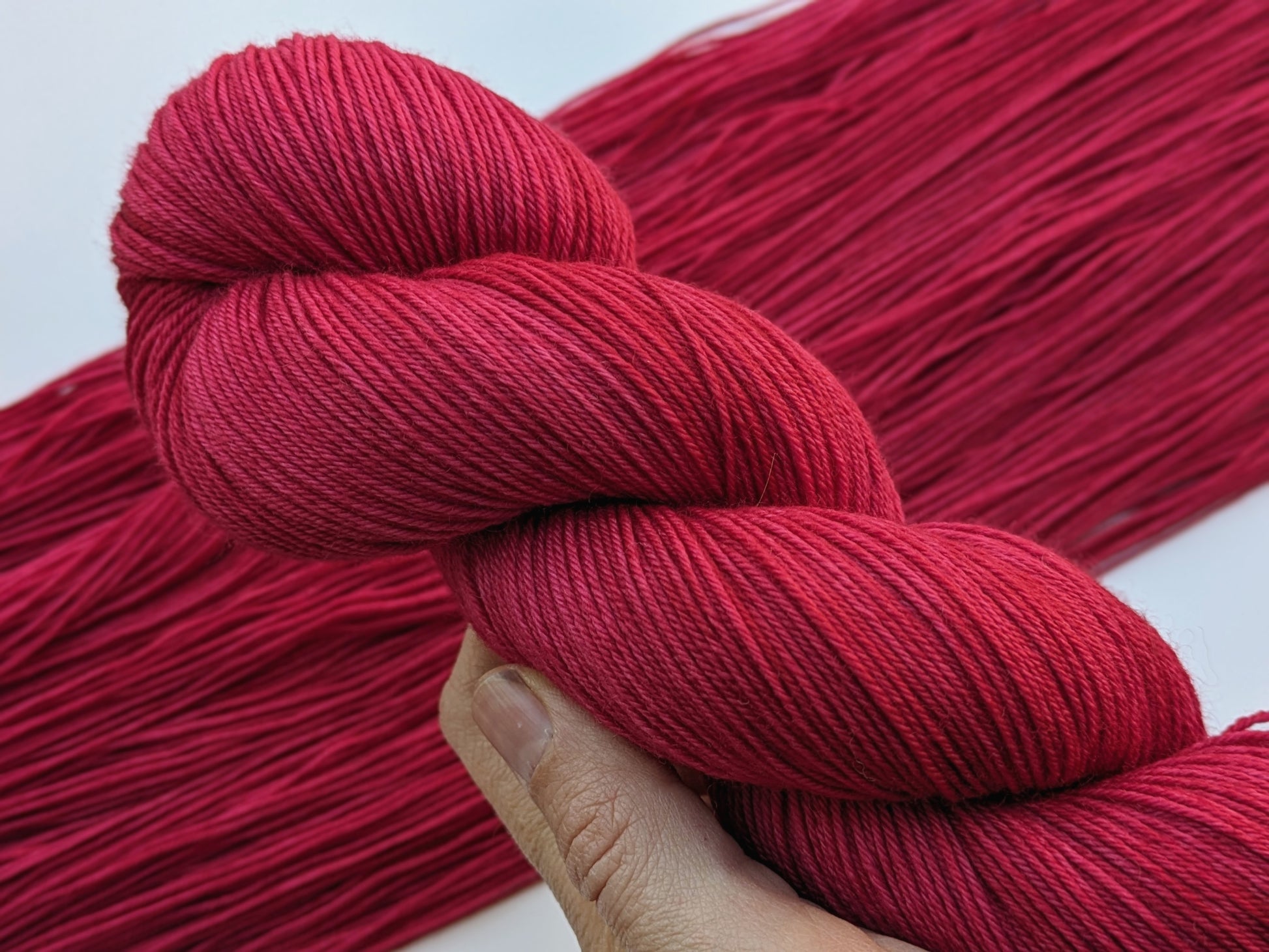 A Good Red Yarn skein in fingering weight, showing vibrant red color