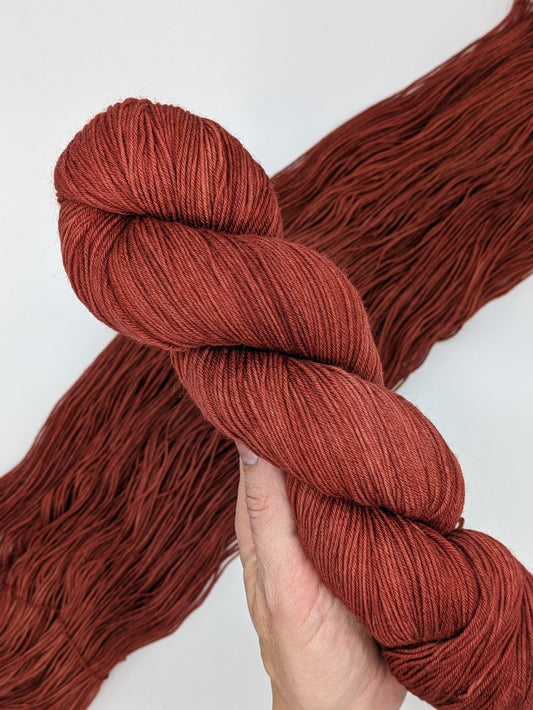 Cinnabar Yarn skein in fingering weight, showcasing vibrant orange-red hues