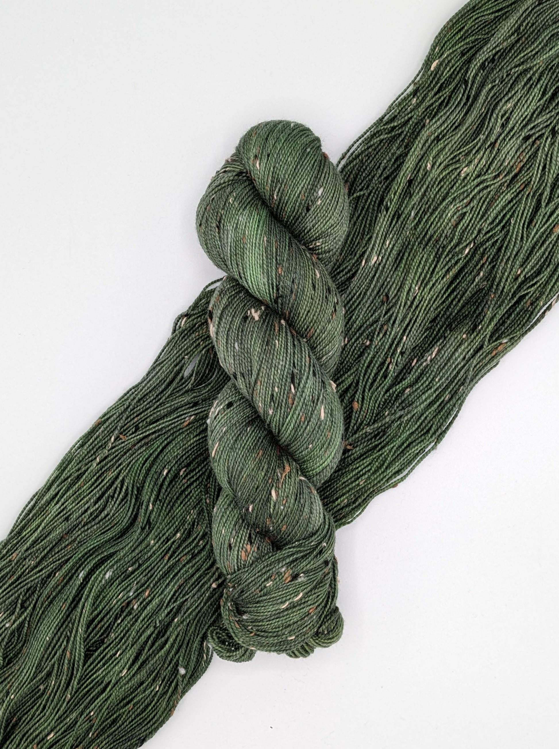 Fir Yarn skein in tweed fingering weight, showcasing rich green color