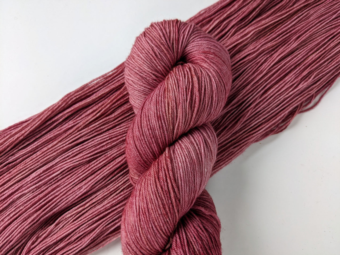 Peony Whisper Yarn skein in fingering weight, showcasing soft peony pink color