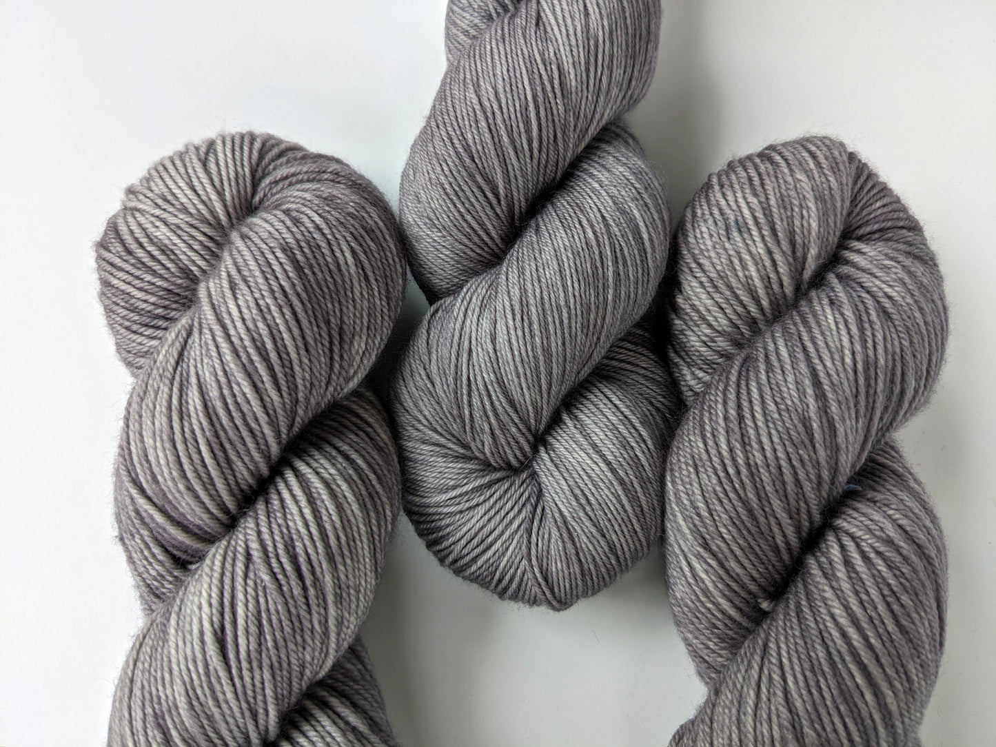 Silver Mist Yarn skeins group in fingering and DK weights, showcasing a soft grey color